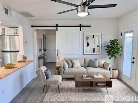 A modern living room with a grey sofa, a wooden coffee table, and a ceiling fan.