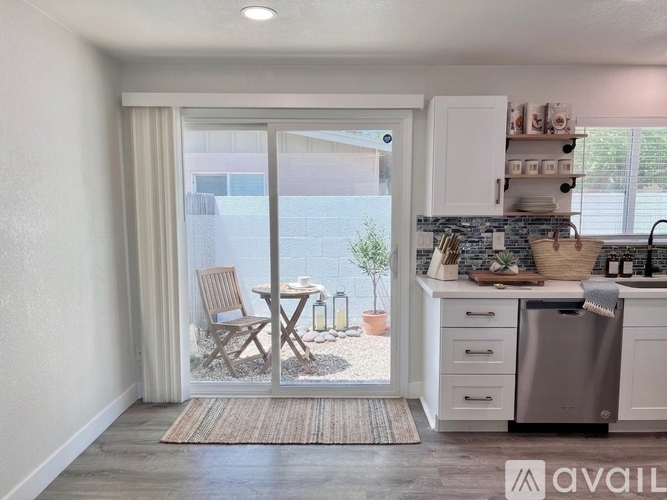 A kitchen with a table and chairs outside through a sliding glass door.