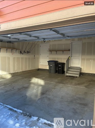 A large empty garage with a red wall and a door.