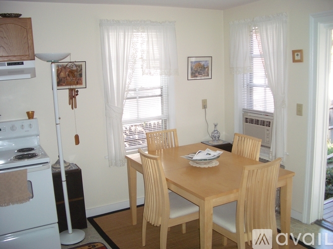 A kitchen with a stove, table and chairs.