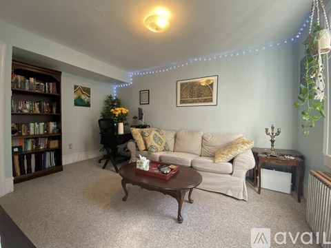 A living room with a grey couch, a brown table, and a mirror on the wall.