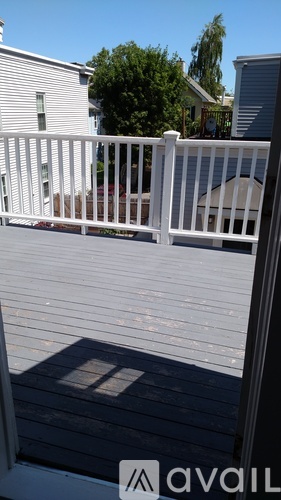 A white fence with a shadow of a tree on a wooden deck.