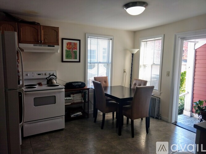 A kitchen with a white refrigerator and a dining table with chairs.