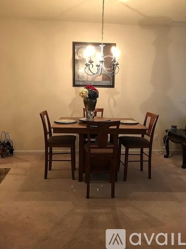 A dining room with a table set for four and a chandelier hanging from the ceiling.