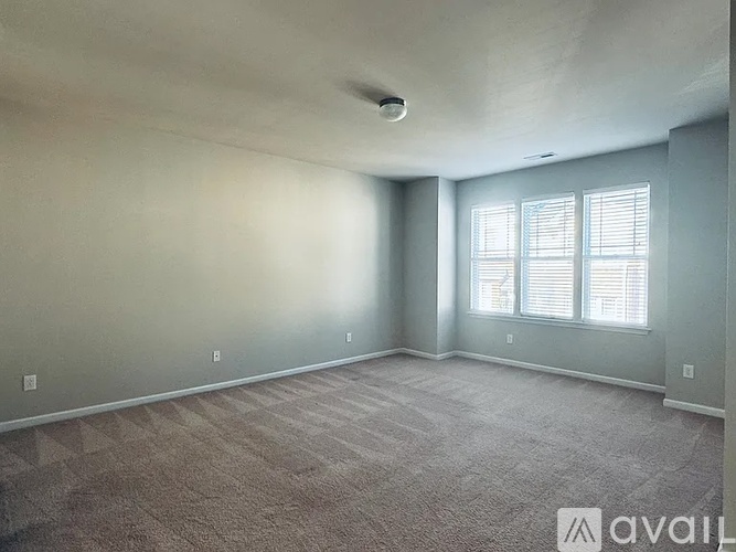 A spacious room with carpeted floor and a window with blinds.