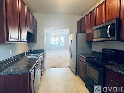 A kitchen with dark wood cabinets and a black countertop.
