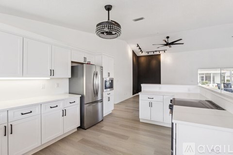 A modern kitchen with white cabinets and a stainless steel refrigerator.