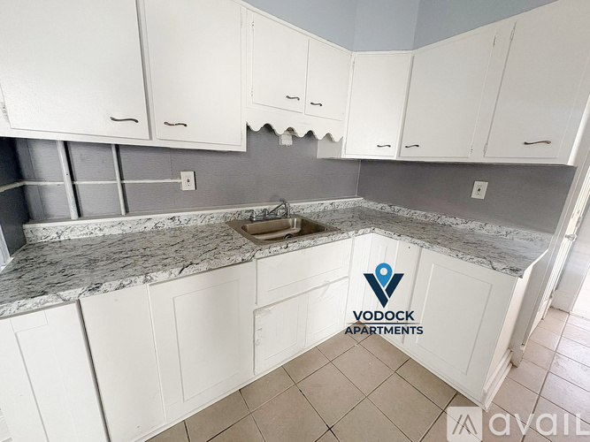 A kitchen with white cabinets and a marble countertop is available for rent.