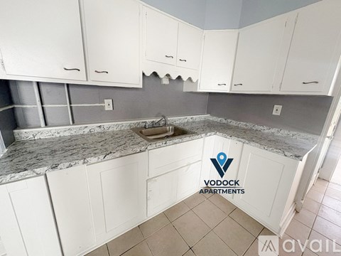 A kitchen with white cabinets and a marble countertop is available for rent.