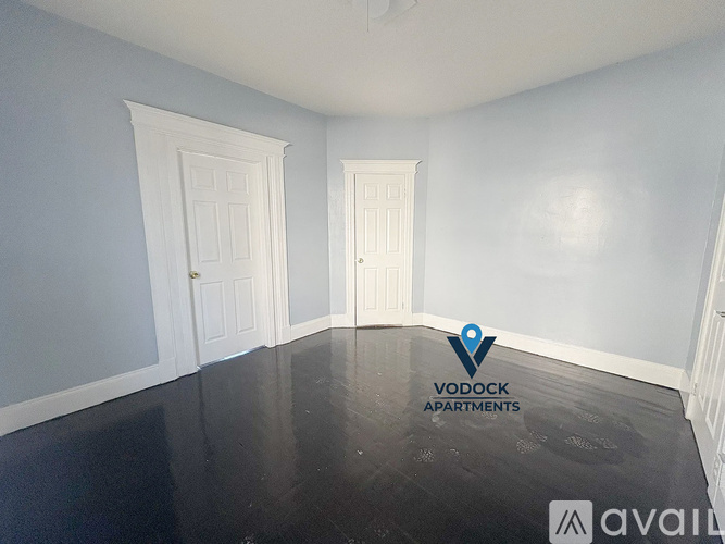 A spacious empty room with two doors and a logo for Vodock Apartments.