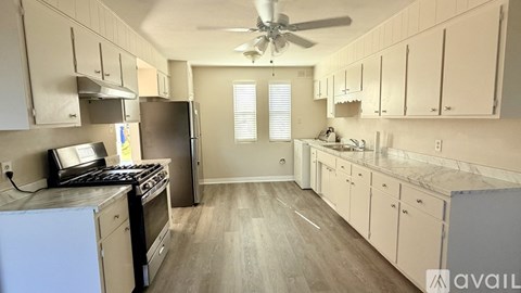 A kitchen with a refrigerator, stove, and cabinets.