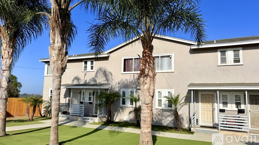 A house with a white fence and a palm tree in front.