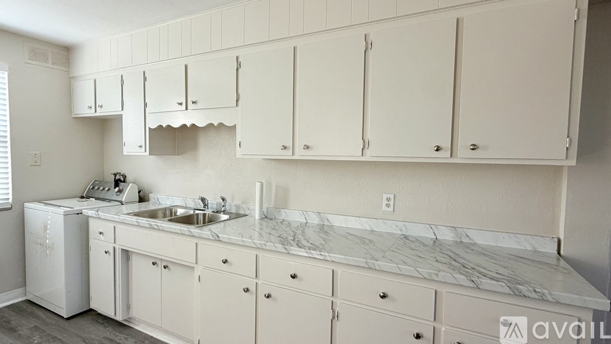 A kitchen with white cabinets and a marble countertop.