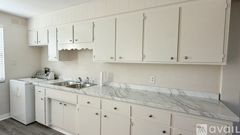A kitchen with white cabinets and a marble countertop.
