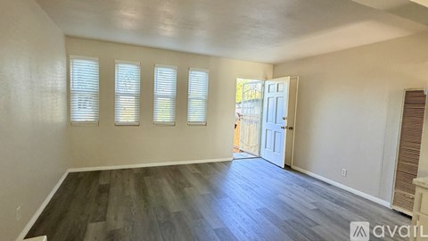 A room with wooden flooring and a door leading to another room.