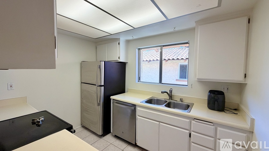 A kitchen with a black fridge, white cabinets, and a black cutting board on the counter.