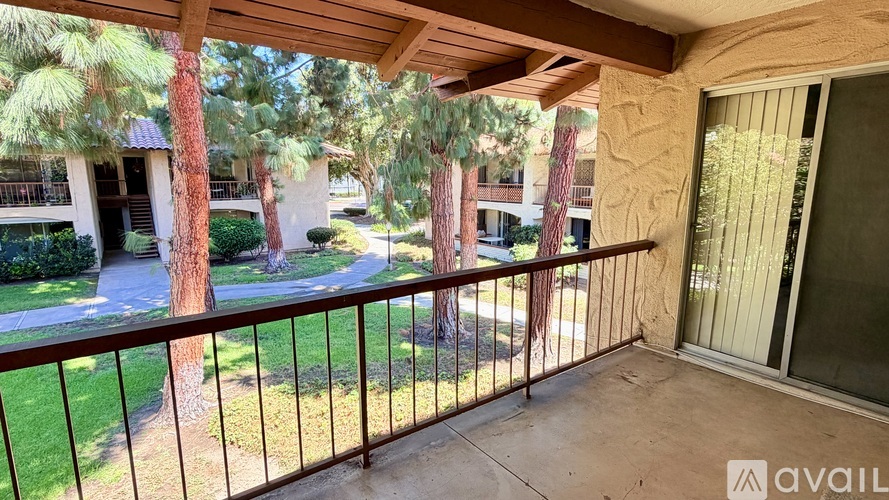 A balcony with a metal railing and a view of a tree and a building.