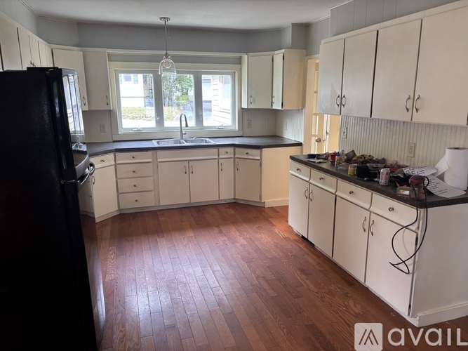 A kitchen with white cabinets and a black refrigerator.
