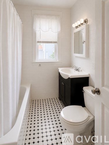 A white toilet sits in a bathroom with a black and white floor.