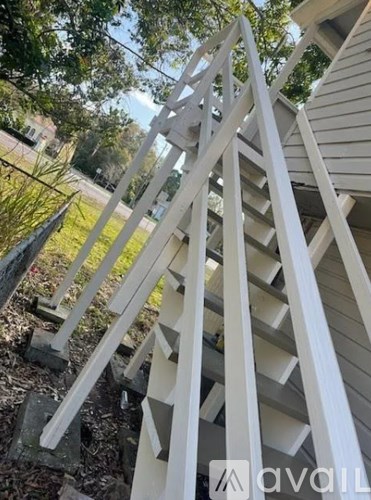 A white wooden staircase with a black railing is in front of a house.