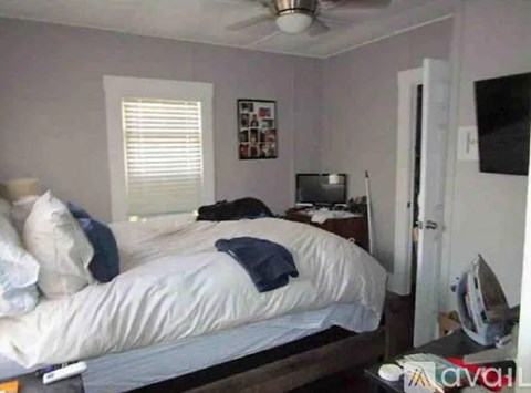 A bedroom with a bed, dresser, and a ceiling fan.