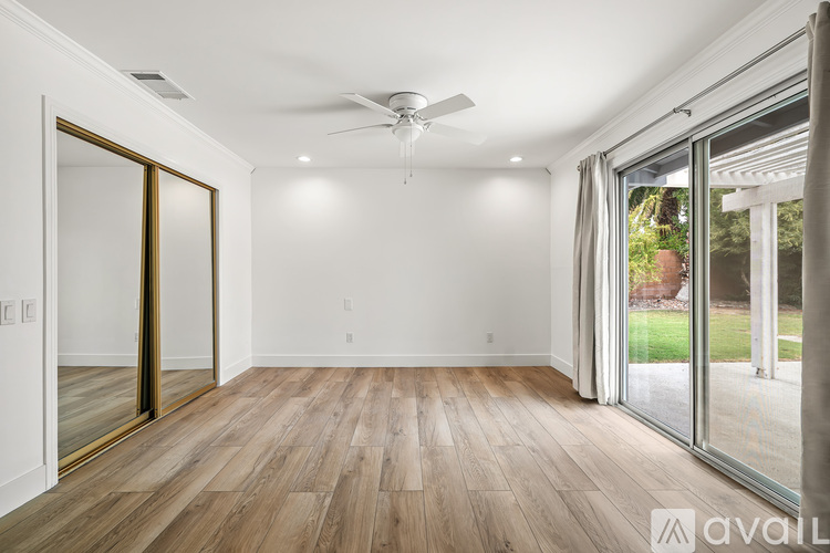 A spacious room with wooden flooring and a ceiling fan.