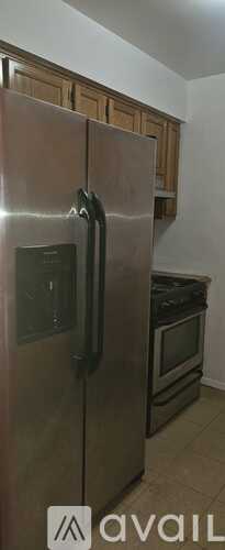 A stainless steel refrigerator with a black handle and a black door.