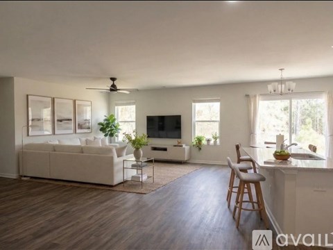 A living room with a white couch, a television, and a dining table with chairs.