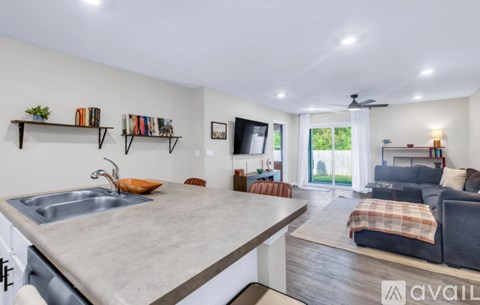 A modern kitchen with a large island and a living room area with a couch and a television.