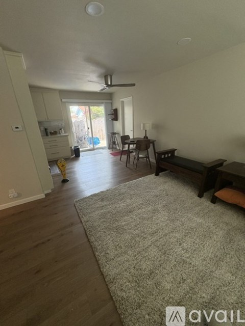 A living room with a grey rug and wooden floors.