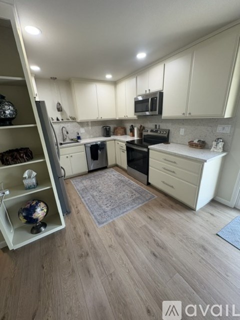 A kitchen with white cabinets and a wooden floor.