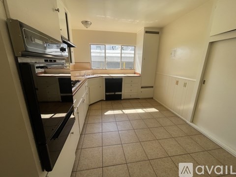 A kitchen with white cabinets and a black fridge.