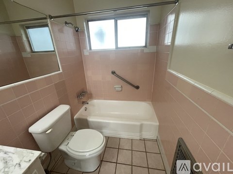 A bathroom with pink tiles and a white toilet and tub.