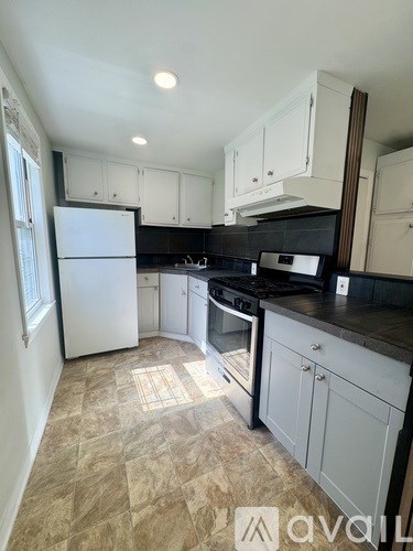 A kitchen with white cabinets and a black countertop.