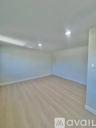 A room with wooden flooring and white walls.