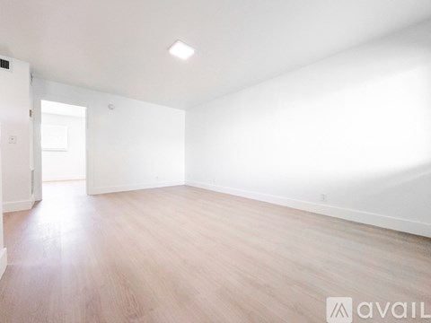 A spacious room with wooden flooring and white walls.