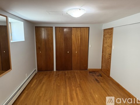 A room with wooden floors and three wooden doors.