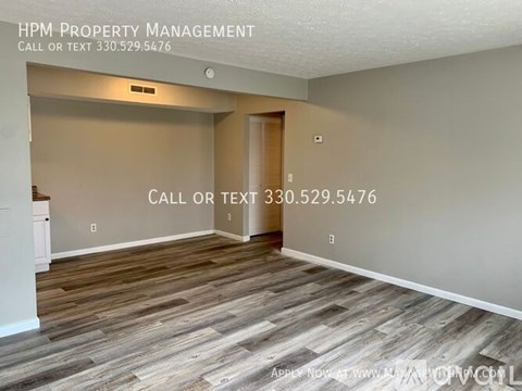 A room with wood flooring and a wall with a phone number for HPM Property Management.