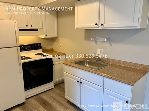 A kitchen with a white refrigerator and cabinets.