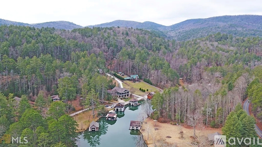 A bird's eye view of a house surrounded by trees and a body of water.