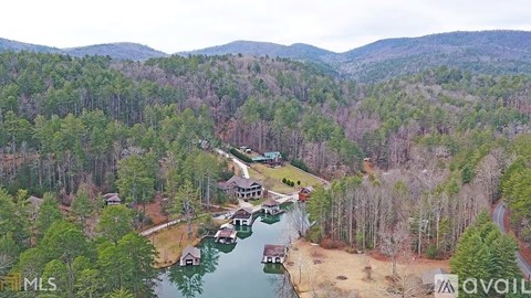 A bird's eye view of a house surrounded by trees and a body of water.