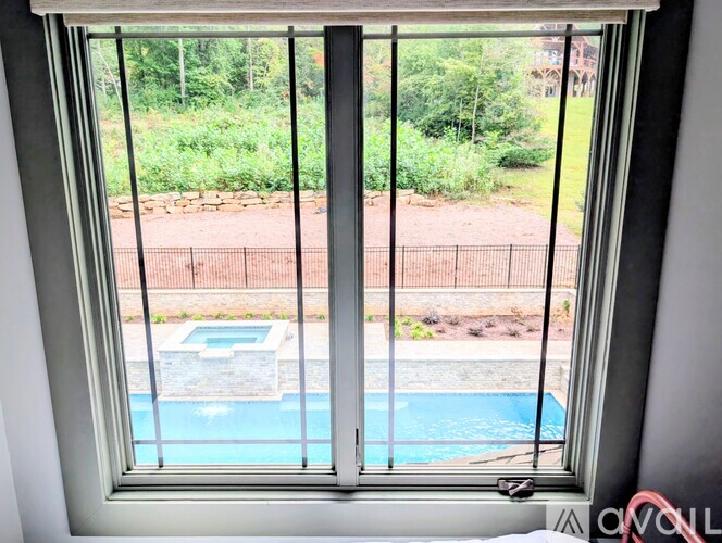A window with a view of a pool and a fence.