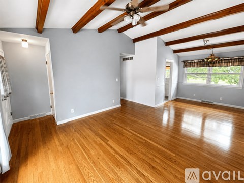 A spacious room with wooden floors and a ceiling fan.