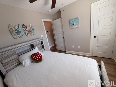 A bedroom with a white bed and a painting of a beach scene on the wall.