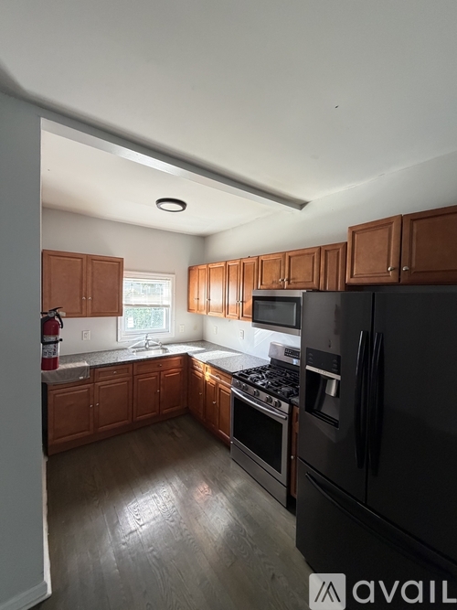 A kitchen with wooden cabinets and a black refrigerator.