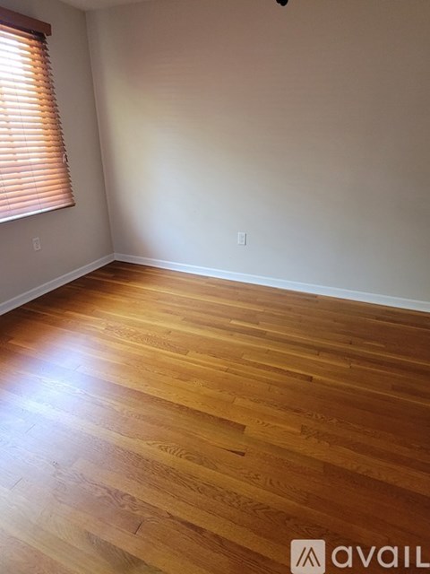 A room with wooden flooring and a window with blinds.