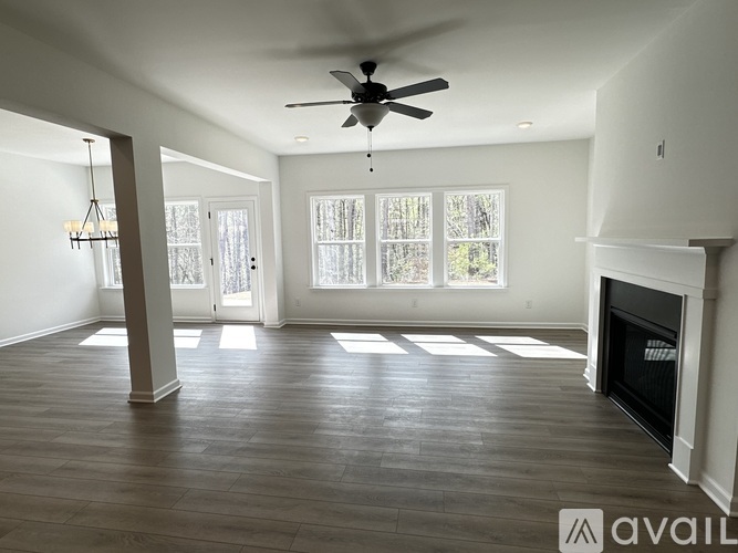 A spacious living room with a fireplace and a ceiling fan.