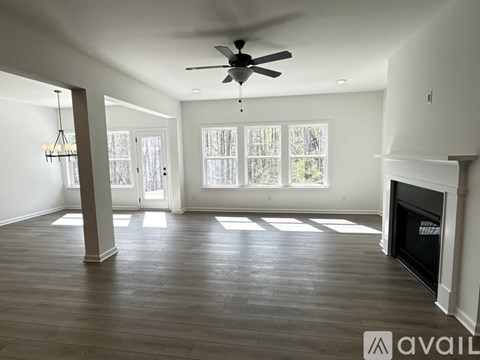 A spacious living room with a fireplace and a ceiling fan.