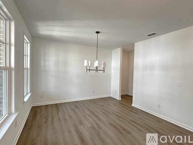 A spacious room with wooden flooring and a chandelier hanging from the ceiling.