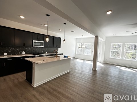 A modern kitchen with dark cabinets and a white island.